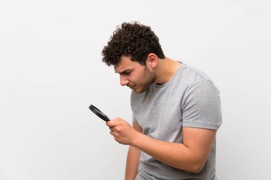 Bir büyüteç tutan izole duvar üzerinde kıvırcık saçlı adam