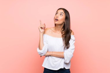 Soyutlanmış pembe arka planı olan genç bir kadın parmak kaldırmayı düşünüyor.