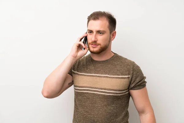 Pohledný Muž Přes Izolovanou Bílou Zeď Používající Mobilní Telefon — Stock fotografie