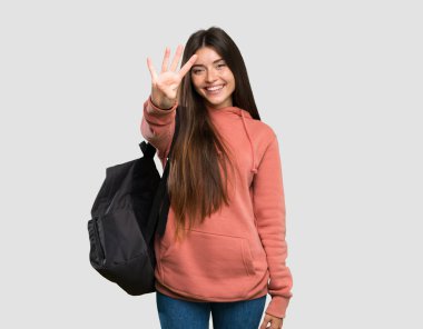 Genç öğrenci kadın defterleri mutlu tutan ve izole gri arka plan üzerinde parmakları ile dört sayma