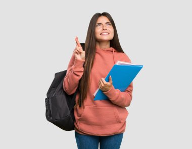 Parmakları geçerken defter tutan ve izole gri arka plan üzerinde en iyi dilek genç öğrenci kadın