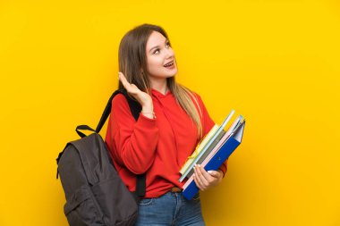 Sürpriz yüz ifadesi ile sarı arka plan üzerinde genç öğrenci kız