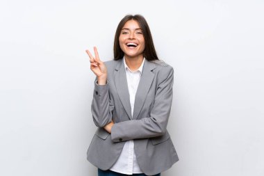 Izole beyaz arka plan üzerinde genç iş kadını gülümseyerek ve zafer işareti gösteren