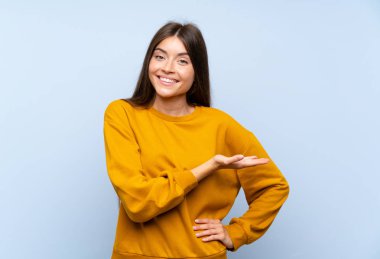 Izole mavi duvar üzerinde Kafkas genç kadın gelmeye davet için elleri yana uzatan