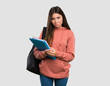 İzole gri arka plan üzerinde hüzünlü ve depresif ifade ile defter tutan genç öğrenci kadın