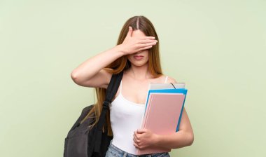 Gözleri elleriyle kaplayan izole yeşil arka plan üzerinde genç öğrenci kadın