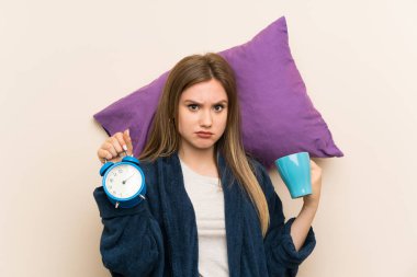 Bir fincan kahve ve vintage saat tutan pijama genç kız