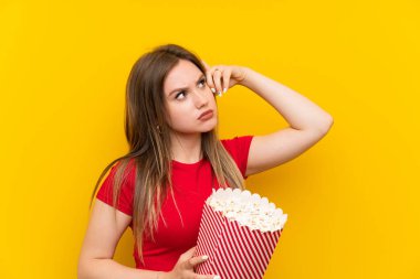 Pembe duvar üzerinde patlamış mısır ile genç kadın şüpheleri olan ve yüz ifadesi karıştırmayın