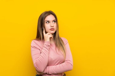 Genç kız üzerinde izole sarı arka plan düşünme bir fikir
