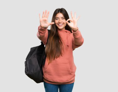 İzole gri arka plan üzerinde parmakları yla sekiz sayma deftertutan genç öğrenci kadın