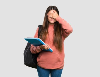 Gözleri elleriyle kaplayan deftertutan genç öğrenci kadın. Yalıtılmış gri arka plan üzerinde bir şey görmek istemiyorum