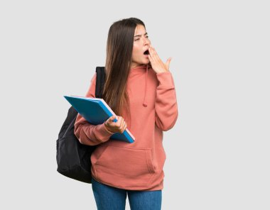 Genç öğrenci kadın dizüstü bilgisayarlar esneme tutan ve izole gri arka plan üzerinde el ile geniş açık ağız kapsayan