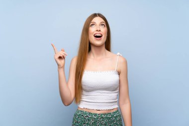 Izole mavi arka plan üzerinde genç kadın işaret ve şaşırttı