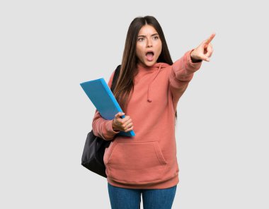 İzole gri arka plan üzerinde işaret defterleri tutan genç öğrenci kadın