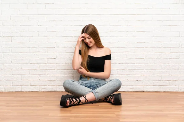 Young woman sitting on the floor laughing