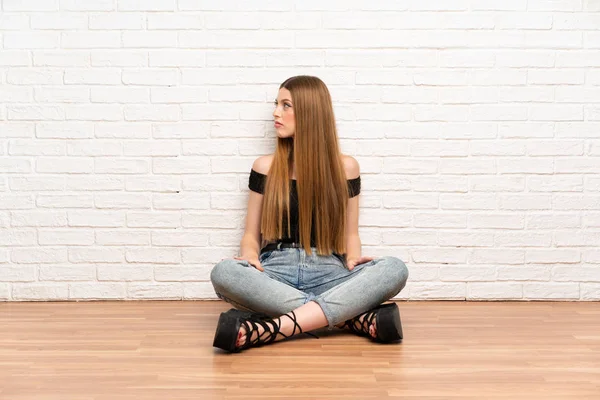 Genç kadın yan bakarak katta oturan