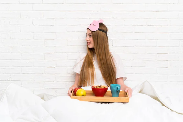 Young woman in dressing gown with breakfast looking to the side