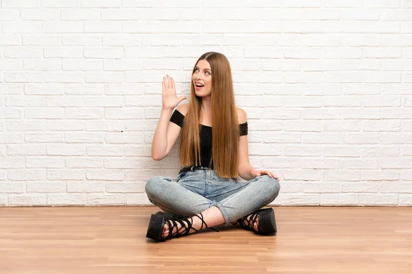 Genç bir kadın yerde oturuyor ve ağzı açık bağırıyor.