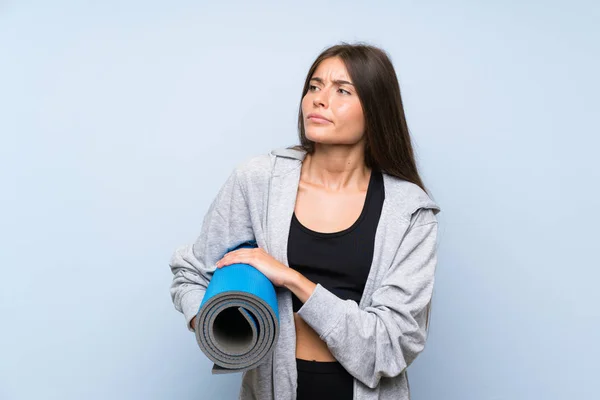 Joven Chica Deportiva Con Estera Sobre Fondo Azul Aislado Haciendo —  Fotos de Stock