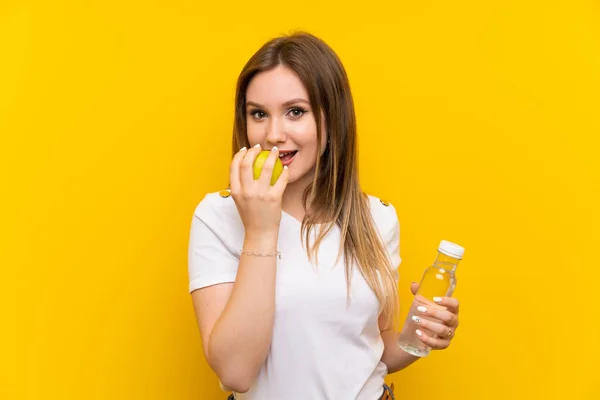 Ragazza Adolescente Sopra Muro Giallo Con Una Mela Una Bottiglia — Foto Stock