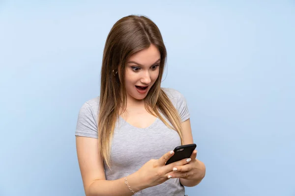 Adolescente Chica Sobre Aislado Azul Pared Sorprendida Envío Mensaje —  Fotos de Stock