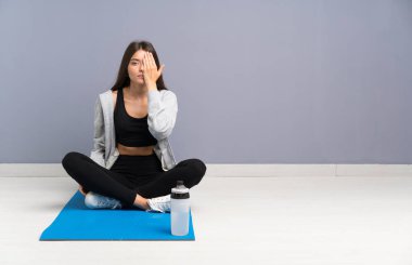 Genç spor kadın mat elle bir göz kapsayan ile katta oturan