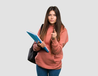 Genç öğrenci kadın dizüstü tutan sinirli ve izole gri arka plan üzerinde ön işaret