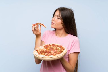 Izole mavi duvar üzerinde bir pizza tutan Pretty genç kız