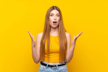 Yüzünde sürpriz ifade olan, izole edilmiş sarı arka planda genç bir kadın.