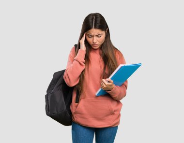 İzole gri arka plan üzerinde baş ağrısı ile defter tutan genç öğrenci kadın