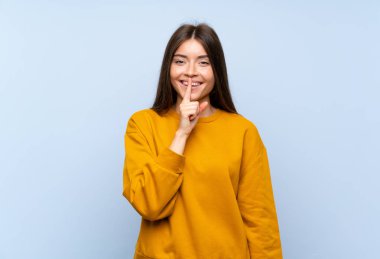 Izole mavi duvar üzerinde kafkas genç kadın sessizlik jestyapıyor