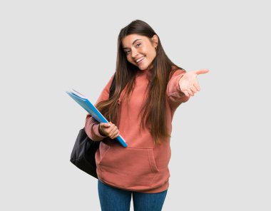 Genç öğrenci kadın sunan defterleri tutan ve izole gri arka plan üzerinde el ile gelmeye davet