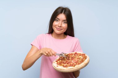 Izole mavi duvar üzerinde bir pizza tutan Pretty genç kız