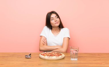 Omuzlarını kaldırırken şüphe jesti yapan pizzalı genç kadın