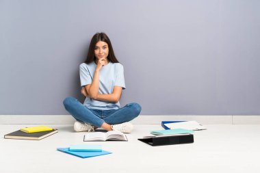 Yerde gülen birçok kitap ile genç öğrenci kadın