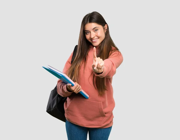 Joven Estudiante Sosteniendo Cuadernos Mostrando Levantando Dedo Sobre Fondo Gris —  Fotos de Stock