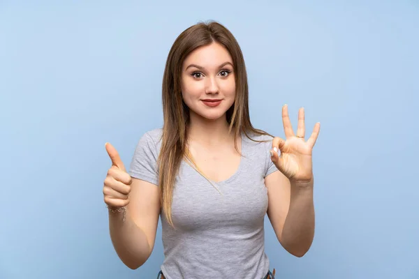 Adolescente Chica Sobre Aislado Azul Pared Mostrando Signo Pulgar Hacia —  Fotos de Stock