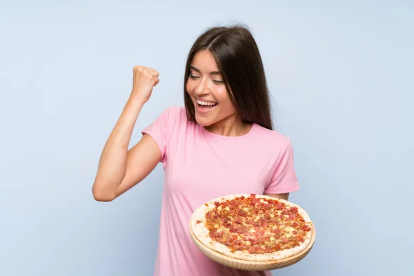 勝利を祝う孤立した青い壁の上にピザを持つかわいい若い女の子 — ストック写真