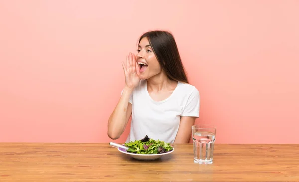 Young woman with a salad shouting with mouth wide open