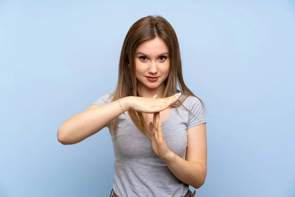 Adolescente Chica Sobre Aislado Azul Pared Haciendo Tiempo Espera Gesto —  Fotos de Stock