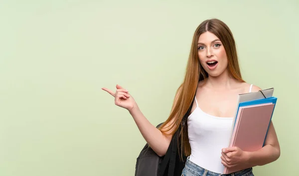 Joven Estudiante Sobre Fondo Verde Aislado Sorprendido Señalando Dedo Hacia —  Fotos de Stock