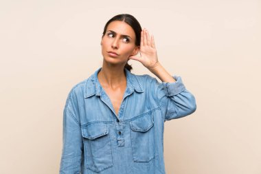 Izole arka plan üzerinde genç kadın kulak elini koyarak bir şey dinlerken