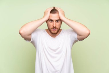 Sürpriz yüz ifadesi ile yeşil arka plan üzerinde yakışıklı adam