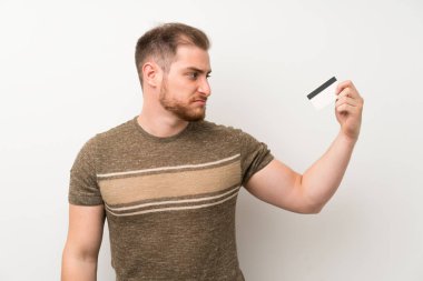 Bir kredi kartı tutan izole beyaz duvar üzerinde Yakışıklı adam