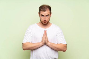 Yeşil arka plan üzerinde yakışıklı adam yalvarıyor