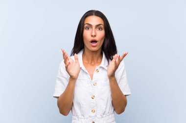 Soyutlanmış mavi arka planı olan genç bir kadın. Şaşırtıcı bir yüz ifadesi.