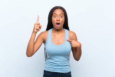 Şaşırtıcı yüz ifade ile izole mavi arka plan üzerinde uzun örgülü saç ile Afrikalı Amerikan Genç kız