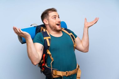 Sürpriz yüz ifadesi ile mavi duvar üzerinde Yürüyüşçü adam