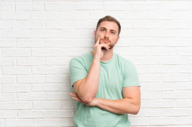 Tuğla duvar üzerinde sarışın adam bir fikir düşünme