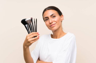 Genç kadın gülümseyerek yukarı bakıyor makyaj fırçası bir sürü tutan